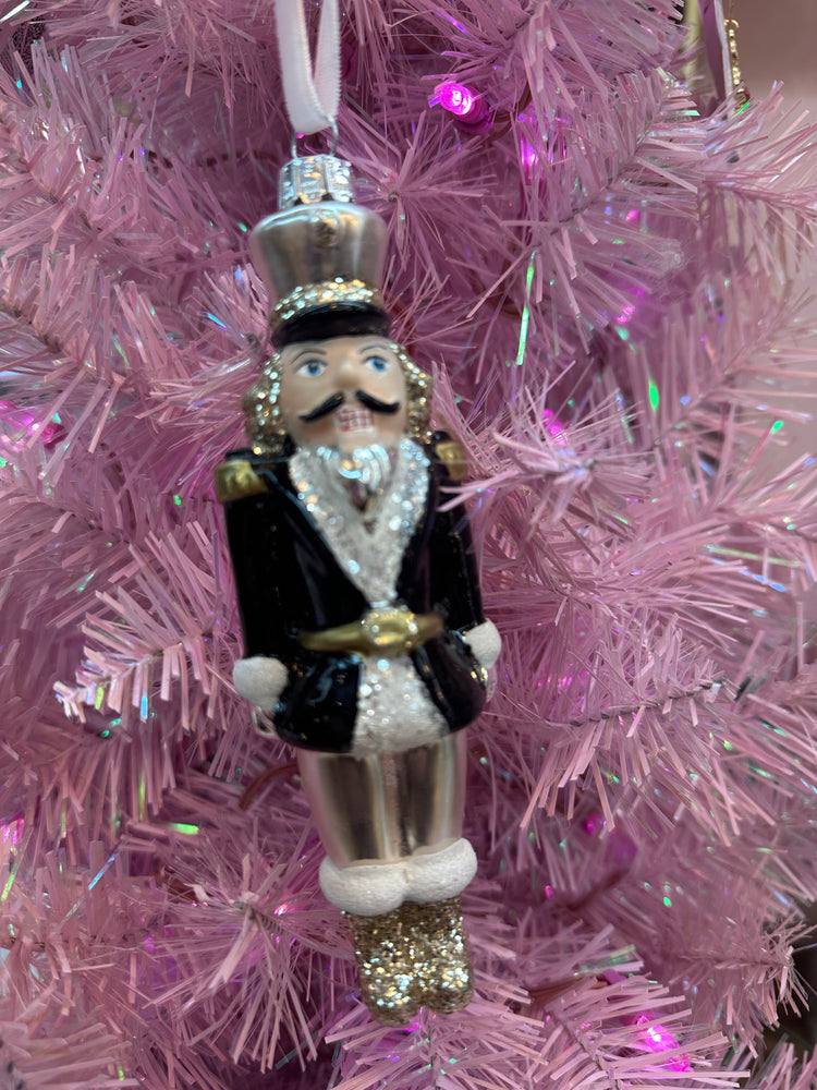 Decorative nutcracker ornament on a pink tinsel background